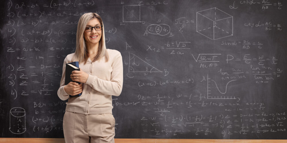 Teacher standing in front of a chalk board with advanced equations on it